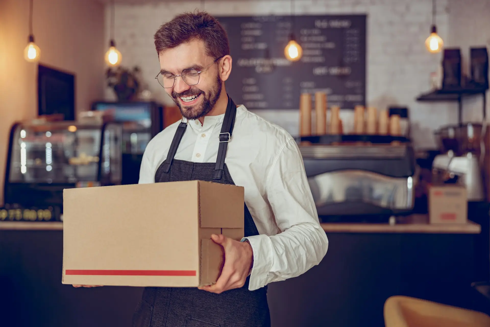 Joyful male worker with parcel standing in coffee shop